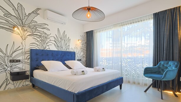 A modern bedroom with a blue bed, white bedding, and a blue chair. - 217 Le Jungle in Cannes (Cannes)