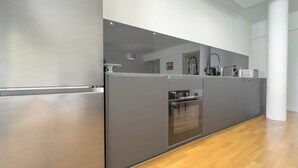 A modern kitchen with a stainless steel refrigerator, a built-in oven, and grey cabinetry. - 213 Le Montfleury in Cannes (Cannes)