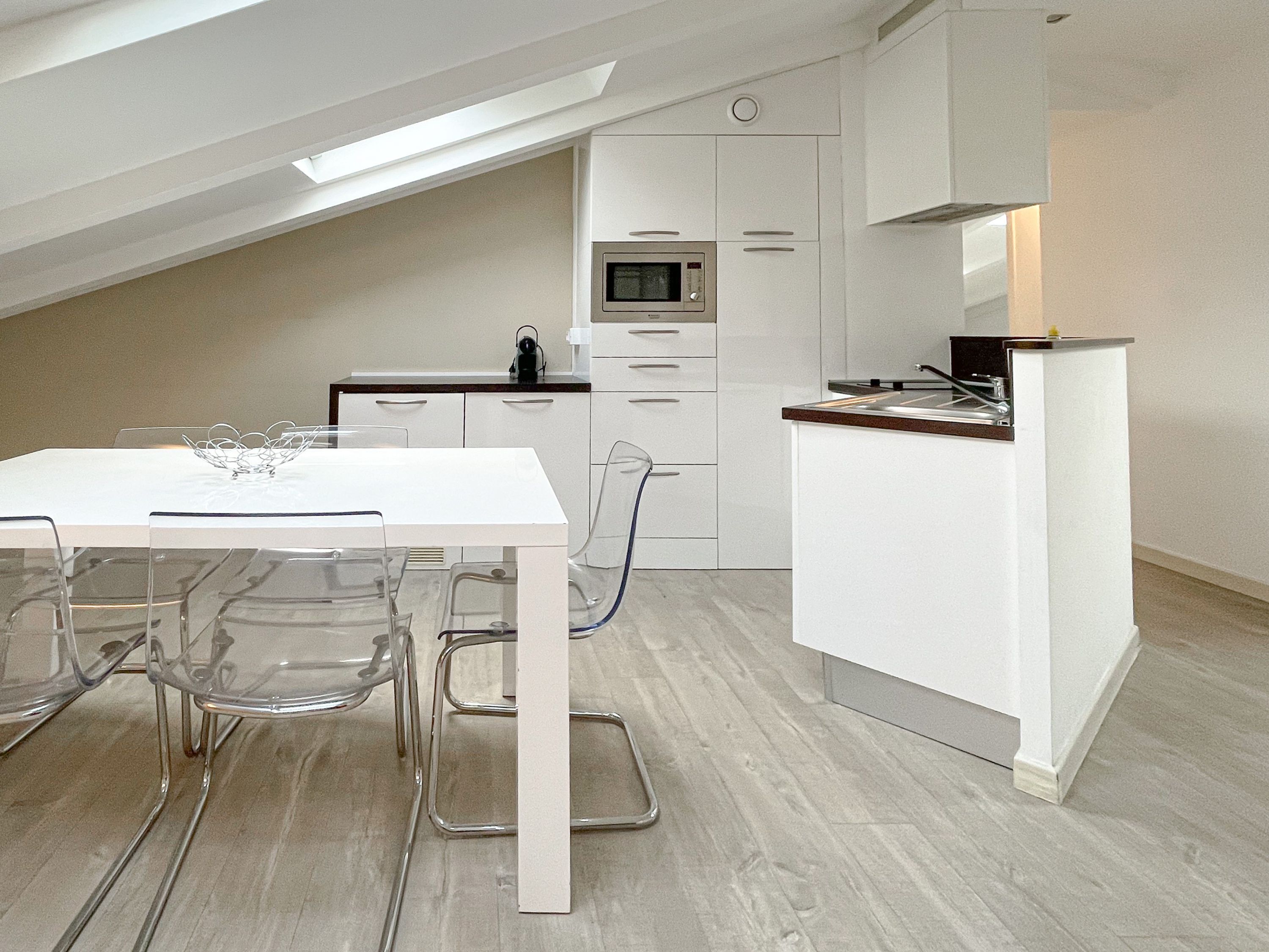Une cuisine moderne avec des meubles blancs, un four à micro-ondes encastré et un plan de travail en bois.