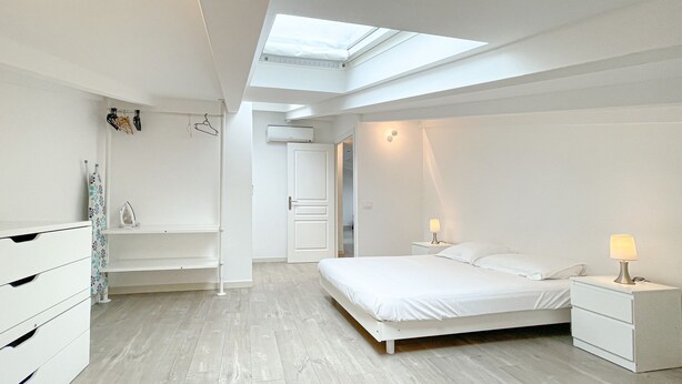 A modern bedroom with a skylight, a bed, a nightstand, and a dresser. - 210 - Tony Allard 4A (Cannes)