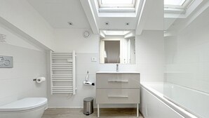 A modern bathroom with a skylight, white fixtures, and a wooden floor. - 210 - Tony Allard 4A (Cannes)