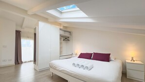 A bedroom with a skylight, a bed with white bedding and rolled towels, a wardrobe, and a bedside table with a lamp. - 4B Tony Allard in Cannes (Cannes)