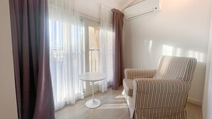 A room with a striped armchair, a small round table, and sheer curtains. - 4B Tony Allard in Cannes (Cannes)