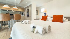 Een moderne hotelkamer met een groot bed, een zithoek met een bar en een kitchenette.