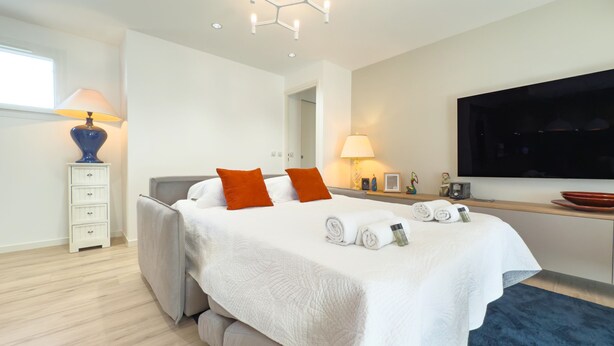 Een moderne slaapkamer met een groot bed, een bureau en een televisie.