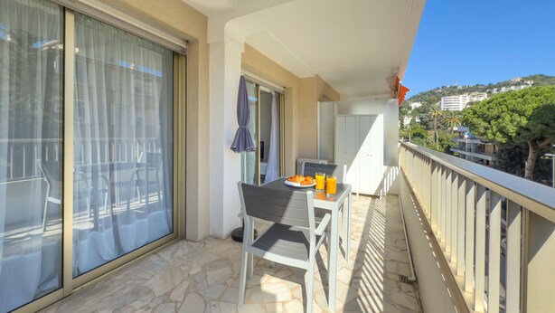 A balcony with a table set for breakfast, a chair, and a view of the city.