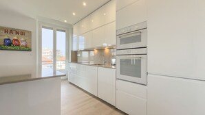 A modern kitchen with white cabinetry, a built-in oven, and a large window.