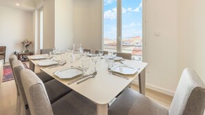En matplats med ett bord för sex personer, stora fönster och utsikt över byggnader.