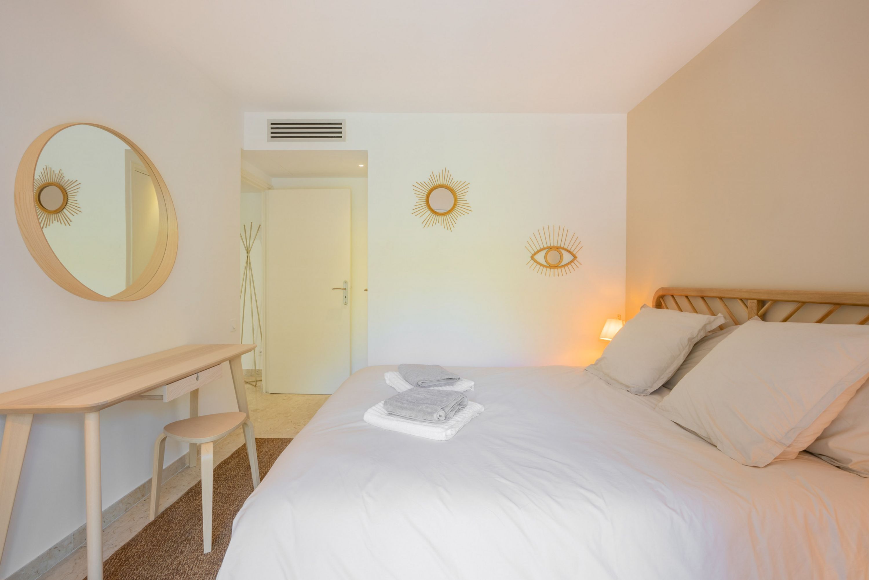A neatly arranged bedroom with a bed, a desk, and a chair.