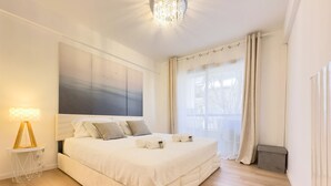 Un dormitorio espacioso con una cama grande, una lámpara de noche y vistas al exterior a través de la ventana.