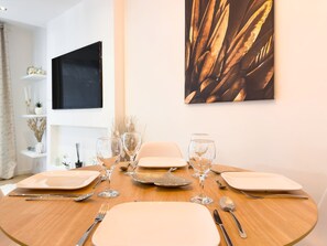 A dining table set with plates, cutlery, and wine glasses, surrounded by a minimalist decor with a painting on the wall. - 310 Le Dor in Cannes (Cannes)