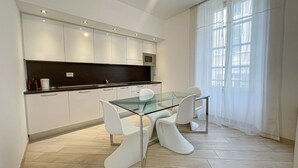 Een moderne keuken met witte kasten, een glazen eettafel en witte stoelen.