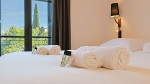 A hotel room with a bed, two rolled towels, a bottle, and a lamp. - 007 Villa Deva in Cannes (Cannes)