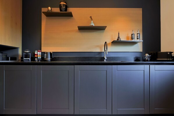 A modern kitchen with dark cabinetry, a black countertop, and a minimalist design.