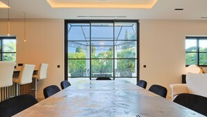 A modern meeting room with a large table, black chairs, and large windows offering a view of greenery. - 007 Villa Deva in Cannes (Cannes)