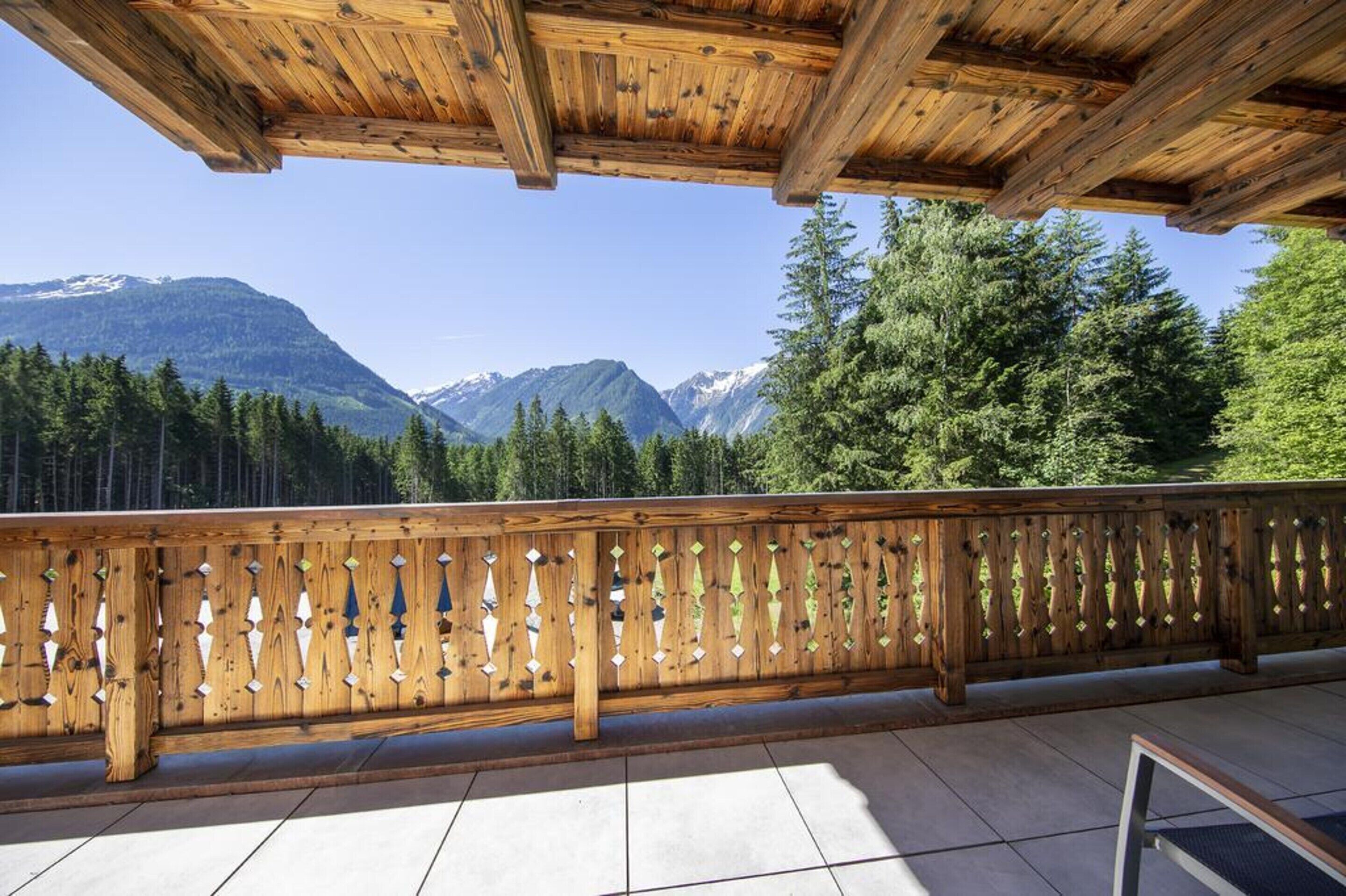 Een houten balkon met uitzicht op bergen en bomen.