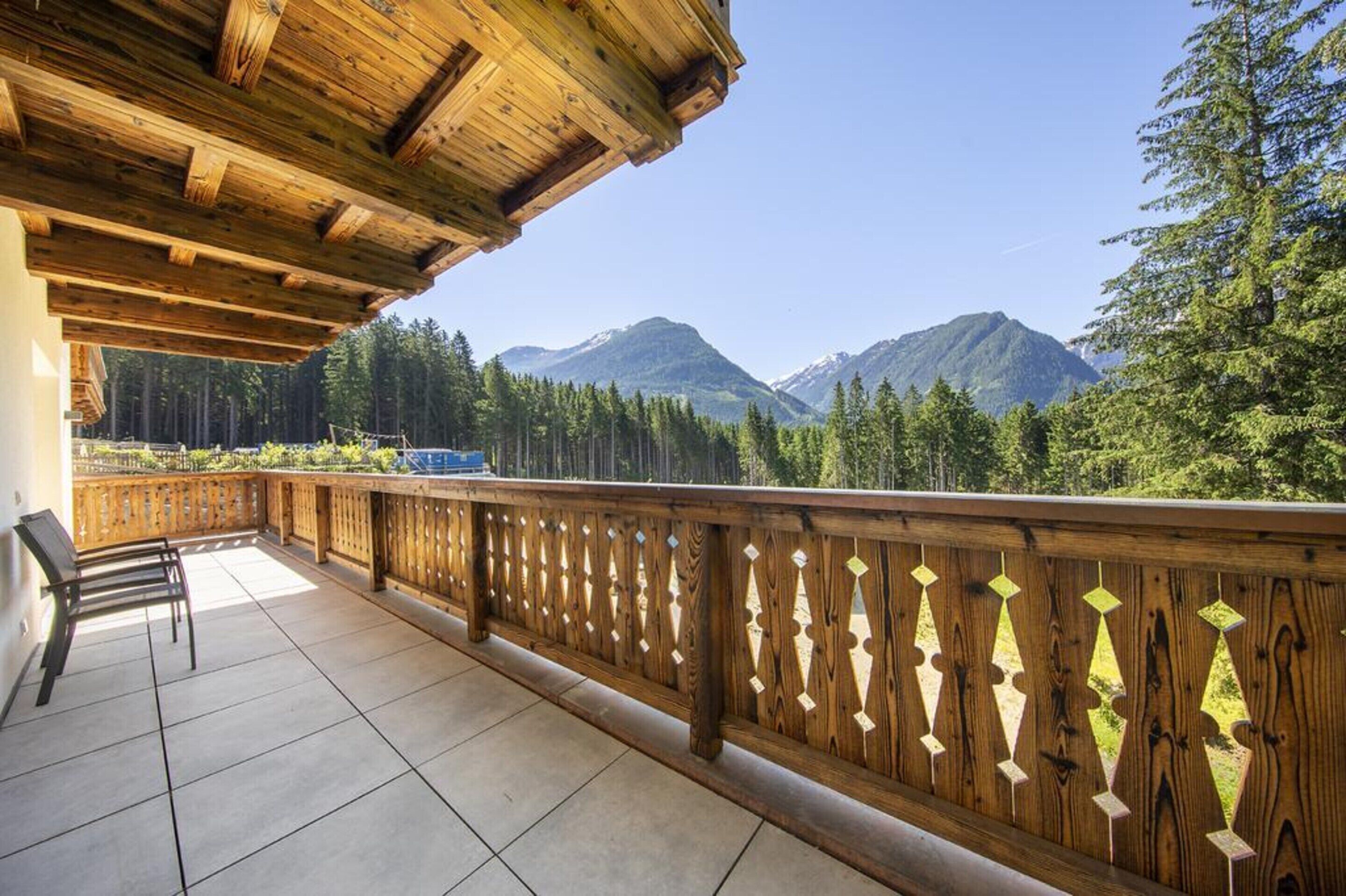A wooden balcony with a view of mountains and trees.