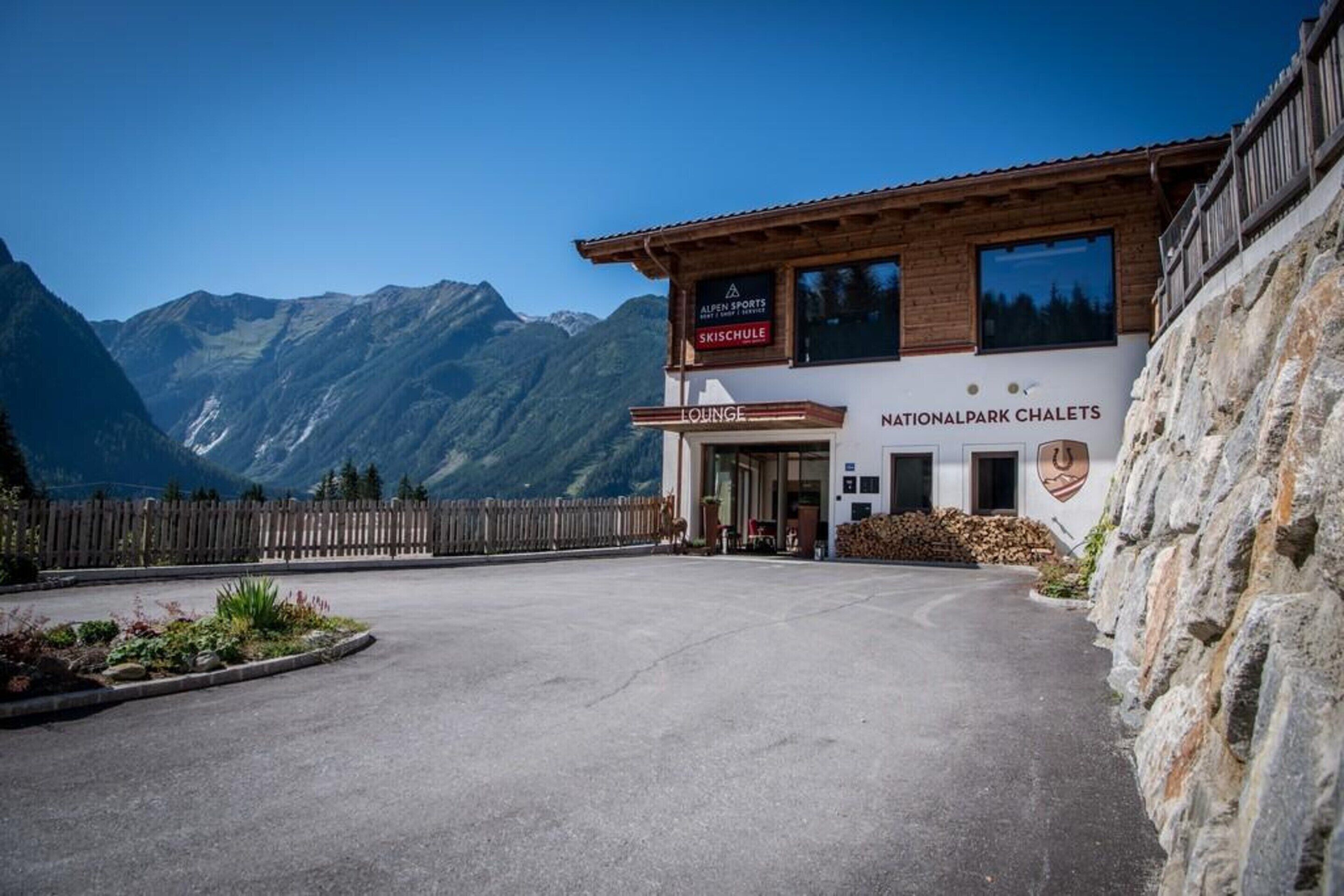 A building labeled "Nationalpark Chalets" with a sign for "Alpen Sports" and "Skischule" visible.