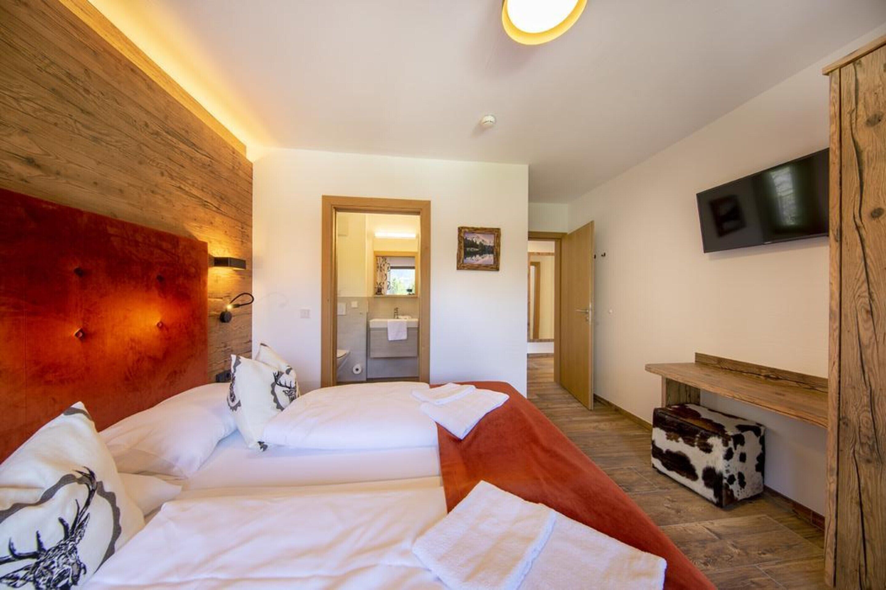 A hotel room with two beds, a wooden headboard, a television, and a small wooden cabinet.