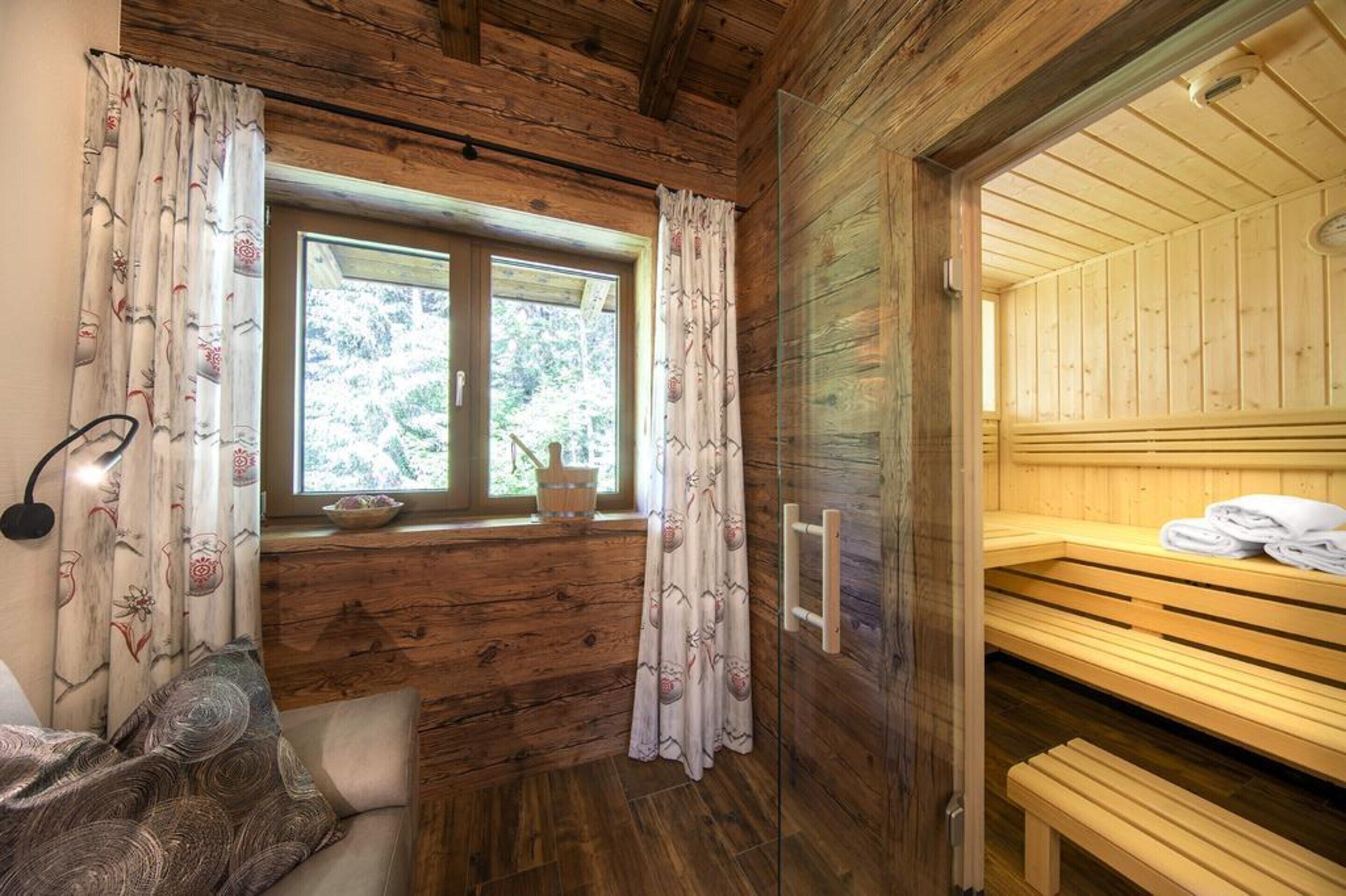 A wooden cabin room with a window, a bench, and a sauna area.