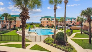 A resort with a swimming pool, palm trees, and a view of the ocean.
