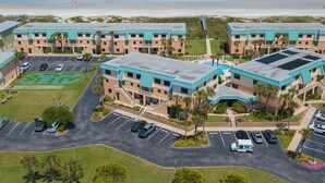 A beachfront hotel with multiple buildings, a parking lot, and a view of the ocean.
