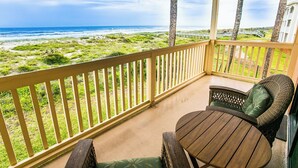 A covered balcony with a view of the ocean and beach.
