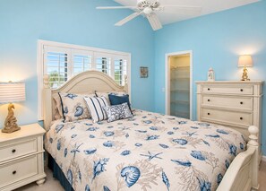 A bedroom with a bed, a nightstand, a dresser, a ceiling fan, and a window with blinds.