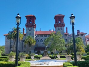 A large historic building with two towers, a central courtyard, and a statue in the middle.