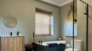 Une salle de bain avec un meuble-lavabo en bois, une baignoire sur pieds, des toilettes et une cabine de douche en verre.