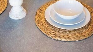 A dining table set with white plates, bowls, and candles, surrounded by woven placemats. - Hidden Paradise｜ BBQ & Fish Pond (Glendora)