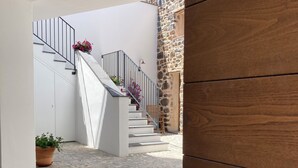 A staircase with a white railing, a stone wall, and a wooden door with a metal handle. - Zenia A - large terrace, sea and mountain view, free private garage (Orosei)