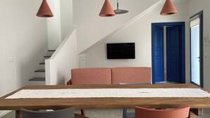 A dining area with a wooden table, four chairs, and three pendant lights. - Zenia A - large terrace, sea and mountain view, free private garage (Orosei)