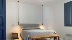 A bedroom with a bed, bedside tables, a bench, and a checkered floor. - Zenia A - large terrace, sea and mountain view, free private garage (Orosei)