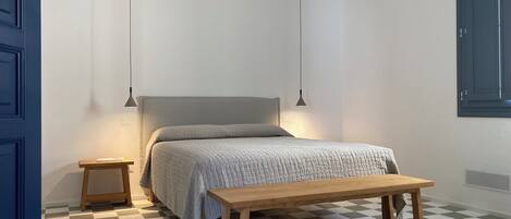 A bedroom with a bed, bedside tables, a bench, and a checkered floor.