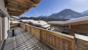 Een houten balkon met uitzicht op besneeuwde bergen en een heldere lucht.
