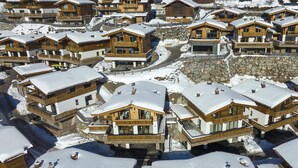 Een groep houten chalets met sneeuw bedekte daken, dicht opeengepakt, vermoedelijk in een bergachtig gebied.