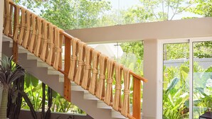Un escalier avec des rampes en corde, une chaise en osier et des lampes en rotin suspendues.