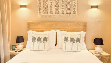 Habitación de hotel con cama, dos mesitas de noche, un adorno en la pared y un cabecero con tallas detalladas.