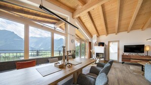Un amplio salón con una mesa de comedor de madera, asientos cómodos, una chimenea y un televisor grande.