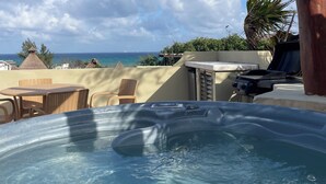 A hot tub with a clear view of the ocean and a thatched-roof structure in the background. - 2BR Kobah • 1 Block to Beach & 5th - Pool+Gym (Playa del Carmen)