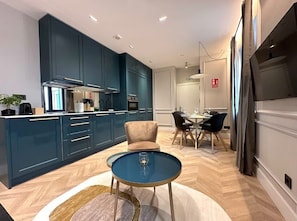 A modern kitchen with dark blue cabinets, a central island, and a dining area with a round table and chairs.