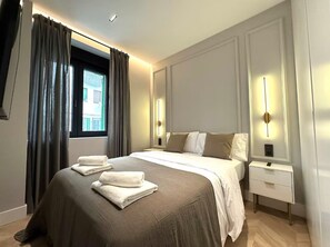 Habitación de hotel con una cama grande, mesitas de noche y una ventana con cortinas.