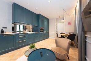 Una cocina moderna con armarios color turquesa, una isla central y un comedor con una mesa redonda y sillas.