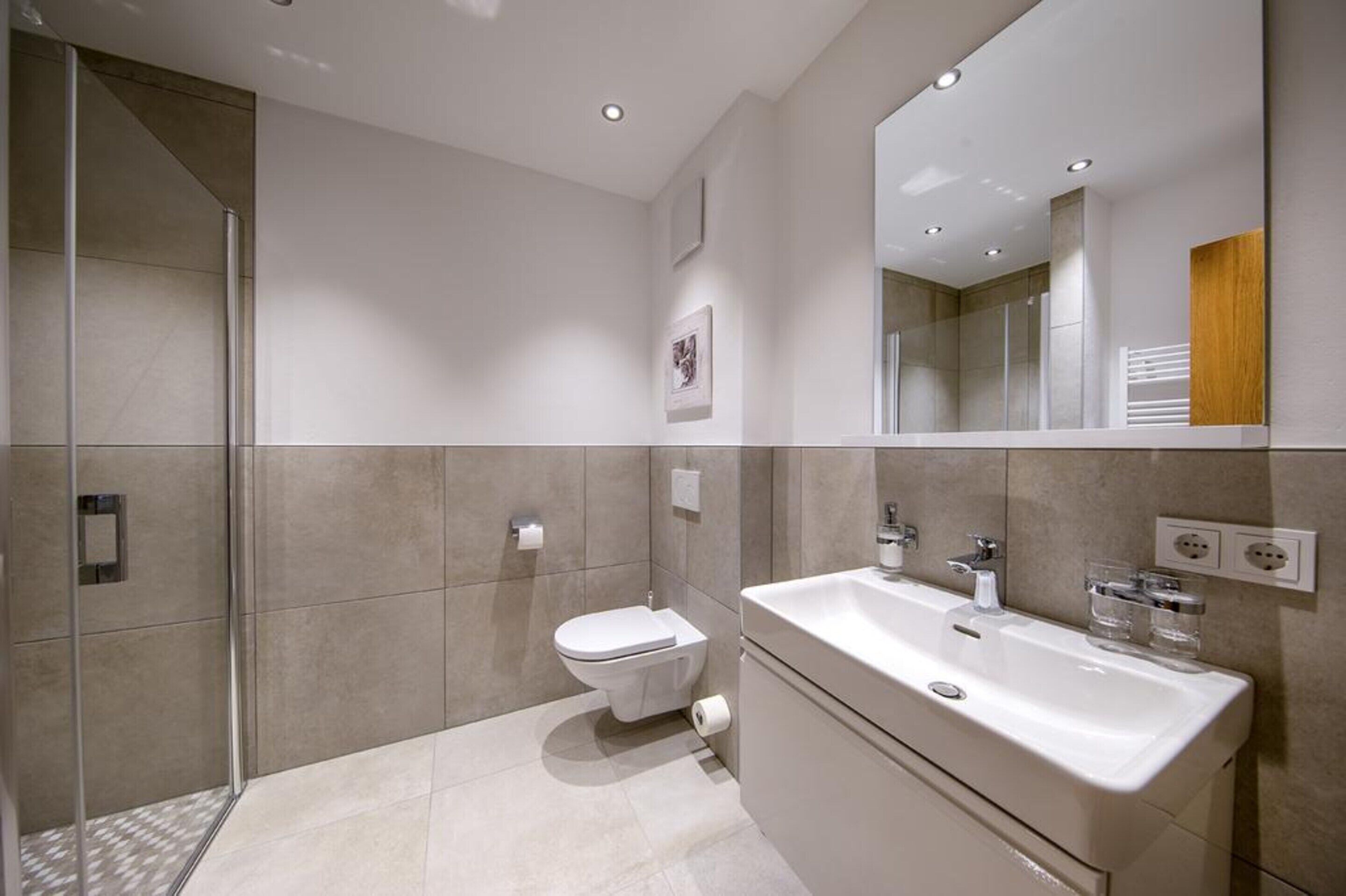 A modern bathroom with a toilet, sink, and shower area.