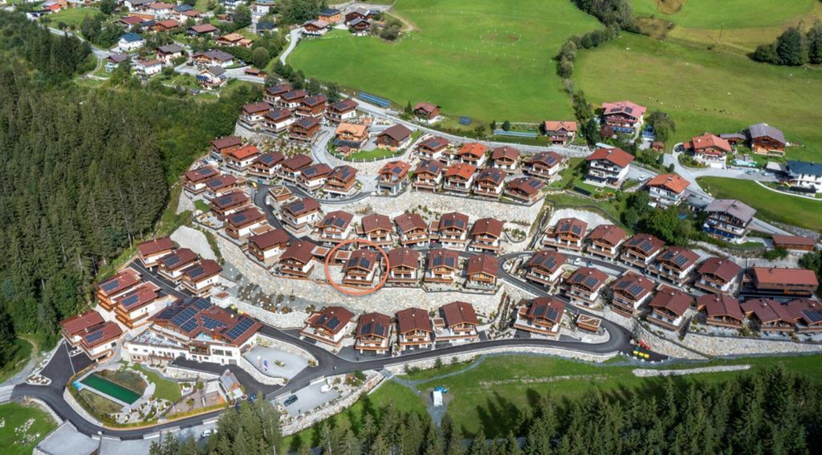 An aerial view of a residential area with houses featuring red roofs and solar panels.