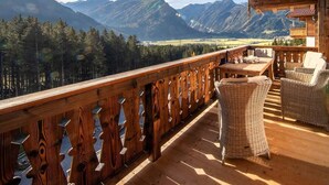 Un terrazzo in legno con mobili in vimini che si affaccia su un paesaggio montuoso.