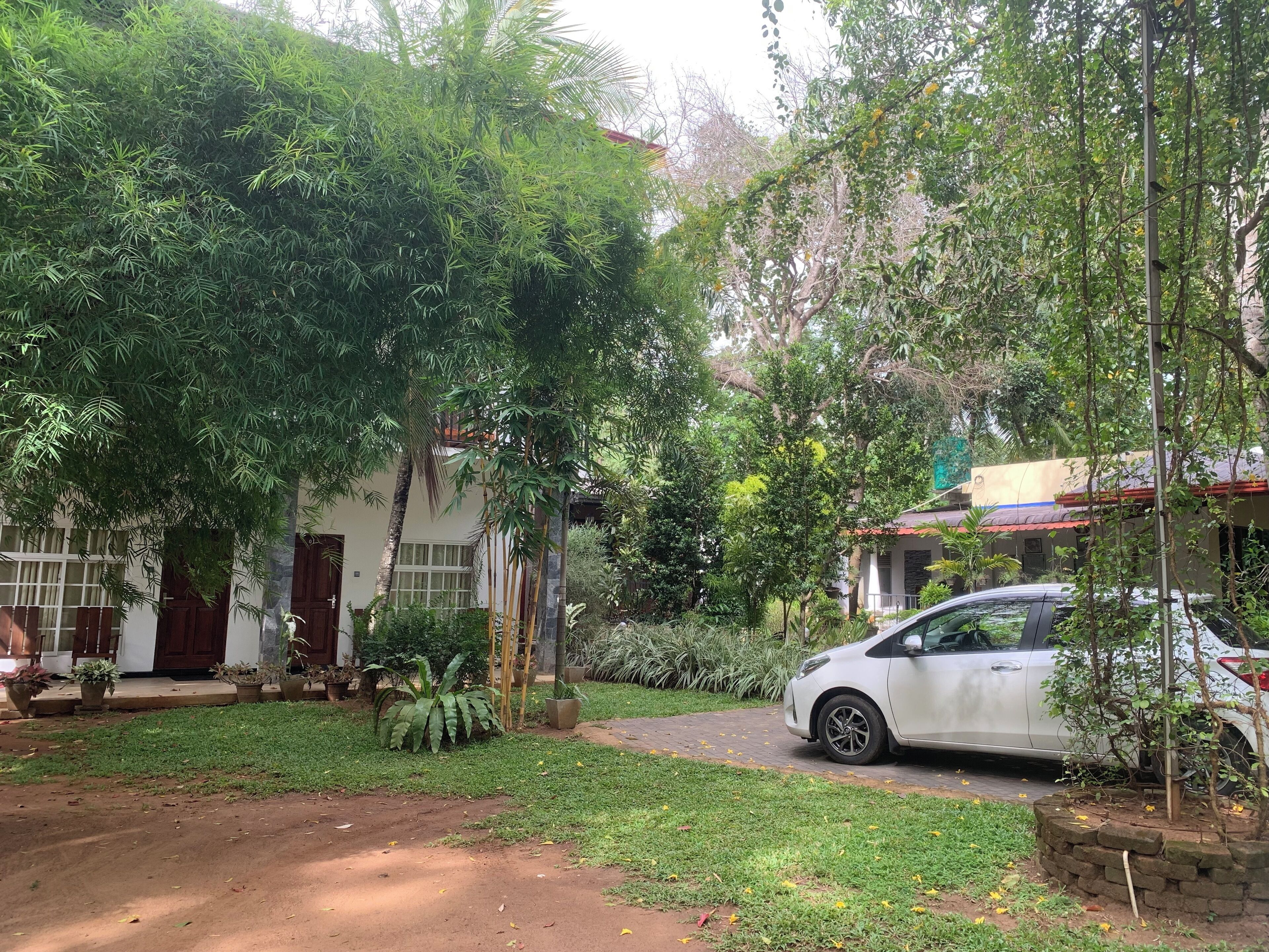 A white car parked in a driveway with a house in the background.