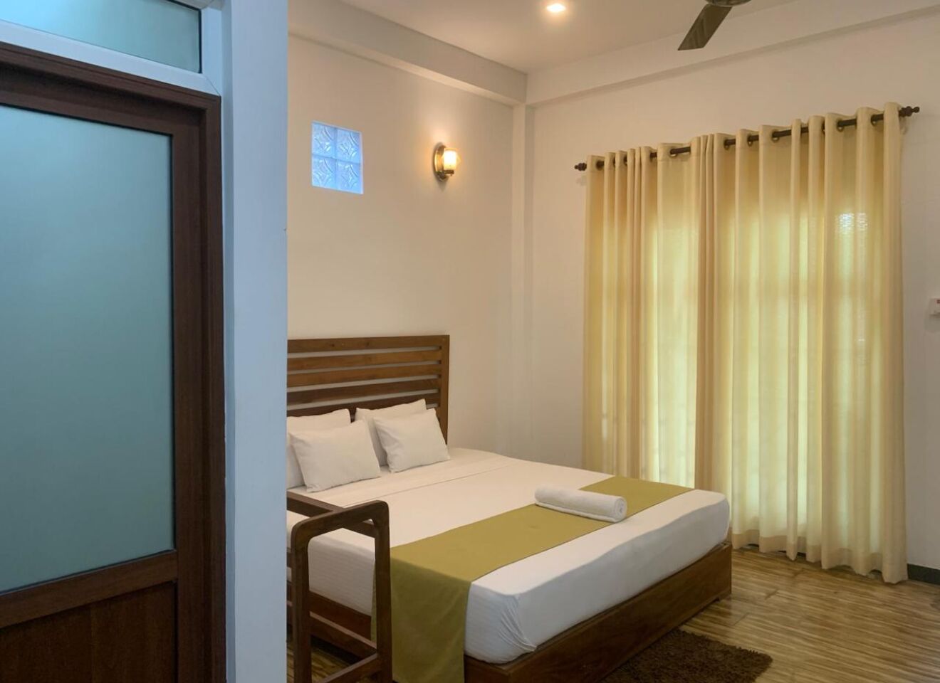 A neatly arranged bedroom with a wooden bed, a small window, and a curtain.