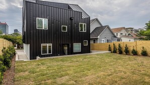 A modern two-story house with a dark exterior, multiple windows, and a well-maintained lawn. - Mini Metro - Downtown Rooftop with Skyline View! (Raleigh)